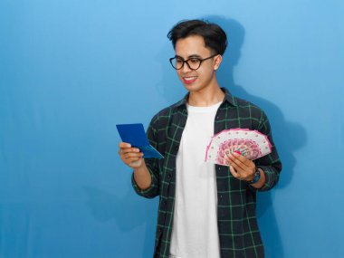 Elinde para tutarken gülümseyen genç bir Asyalı adamın portresi. Tasarruf defterine bakıyor. Mali durumundaki heyecan ve güveni gösteriyor..