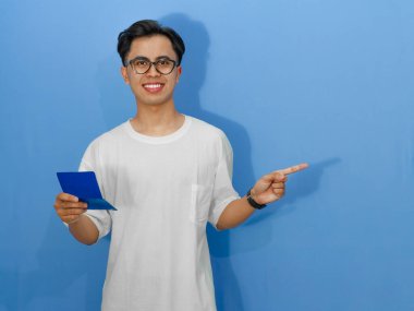 Beyaz tişörtlü mutlu bir Asyalı banka tasarruf kitabıyla poz veriyor..
