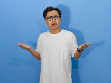 Beyaz tişörtlü, kafası karışmış bir Asyalı adamın portresi. Belirsizliği ifade etmek için mükemmel..
