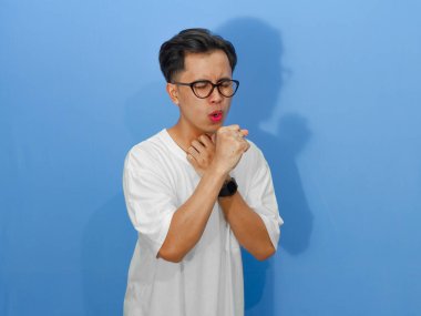 Beyaz tişörtlü sağlıksız bir Asyalı adamın portresi, öksürürken üzüntü ve acı ifade ediyor..