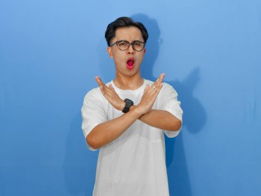 Beyaz tişörtlü ciddi bir Asyalı, güçlü bir mesaj iletmek için kendine güvenen bir dur işareti gösteriyor..