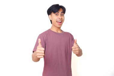 Mutlu, kendine güvenen genç adam kameraya izole edilmiş arka planda iyi niyet göstergesi olarak gülümsüyor. İş, yaşam tarzı ve reklam içeriği için mükemmel..