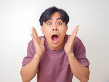 Açık ağızlı ve el kaldıran komik Asyalı genç adam arka planda kameraya bakarken şok tepkisi gösteriyor. Duygular ve yaşam tarzı konsepti için mükemmel..