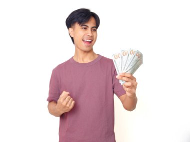 Elinde para ve başarıyı kutlayan mutlu Asyalı genç adam, beyaz arka planda izole edilmiş, finans, zenginlik, iş veya başarı kavramı.