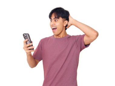 Mutlu Asyalı genç adam akıllı telefonu açık ağızla tutuyor ve elleri kaldırıyor. Heyecanlı, şaşırmış tepkiler gösteriyor..