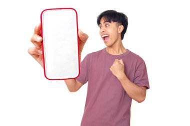 Mutlu Asyalı genç adam kutlarken düz arkaplanda boş akıllı telefon ekranı gösteriyor. Dijital reklam, uygulama tanıtımı ve pazarlama tasarımı için mükemmel..
