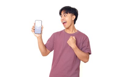 Mutlu Asyalı genç adam kutlarken düz arkaplanda boş akıllı telefon ekranı gösteriyor. Dijital reklam, uygulama tanıtımı ve pazarlama tasarımı için mükemmel..
