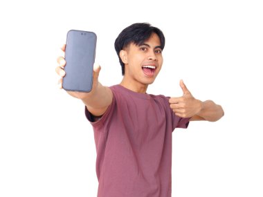 Mutlu Asyalı genç adam boş bir akıllı telefon ekranı göstererek dijital reklamlar, uygulama tanıtımı ve pazarlama tasarımı için mükemmel arka planda başparmak kaldırıyor..