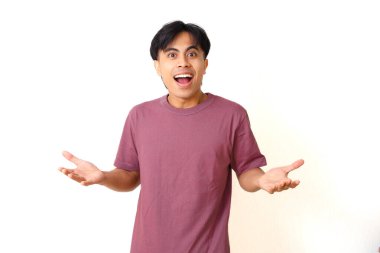 Şaşırmış Asyalı genç bir adam ağzı açık ve el kaldırdı. İzole edilmiş beyaz arka planda sürpriz tepkiler gösteriyor. Şaşırma, duygu ve beklenmedik haberler kavramı..