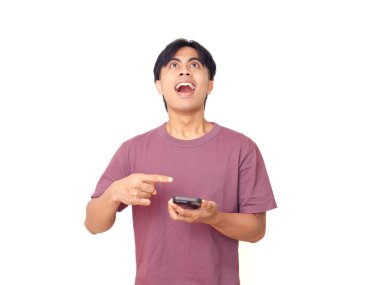 Akıllı telefonu işaret eden mutlu genç Asyalı adam arka planda heyecanlı bir yüz ile dijital reklamlar, uygulama tanıtımı ve çevrimiçi pazarlama için mükemmel..