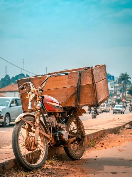 Stock image Close up of a boda boda motorbike used for carrying goods, also known as Bajaj Boxer. The bike is parked on a dusty street of the city Fort portal, in Uganda. There traffic at the background.