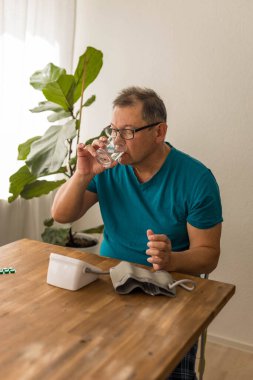 Yaşlı adam odadaki üst koldaki monitörle kan basıncını ölçüyor. Yüksek kalite fotoğraf