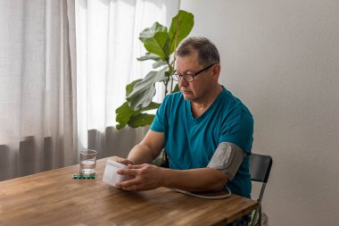 Yaşlı adam odadaki üst koldaki monitörle kan basıncını ölçüyor. Yüksek kalite fotoğraf