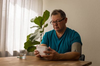 Yaşlı adam odadaki üst koldaki monitörle kan basıncını ölçüyor. Yüksek kalite fotoğraf