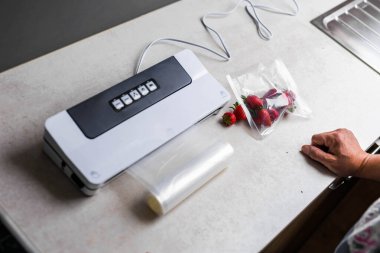 Bir adamın eli vakum makinesi kullanarak çilekleri plastik poşetlere boşaltıyor. - Evet. Yüksek kalite fotoğraf