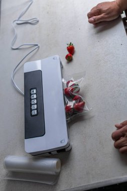Bir adamın eli vakum makinesi kullanarak çilekleri plastik poşetlere boşaltıyor. - Evet. Yüksek kalite fotoğraf