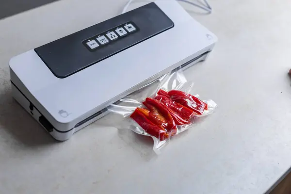 stock image  Sealing machine vacuum packing with plastic bag of red pepper at white table, closeup. High quality photo