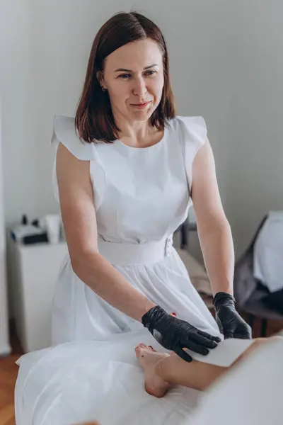 Güzellik uzmanı spa merkezinde sıvı şekerle genç kadınların bacaklarını tükürüyor. Yüksek kalite fotoğraf