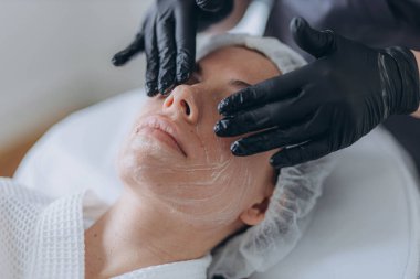 Çekici bir kadının portresi kremalı yüz masajı yaptırıyor. - Evet. Yüksek kalite fotoğraf