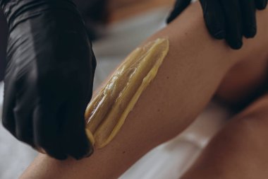 Güzellik uzmanı spa merkezinde sıvı şekerle genç kadınların bacaklarını tükürüyor. Yüksek kalite fotoğraf