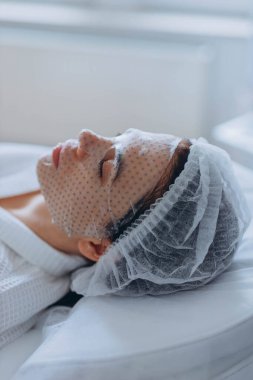 Genç ve güzel bir kadın güzellik salonlarında tedavi görüyor. Yüz maskesi kullanıyor. Yüksek kalite fotoğraf