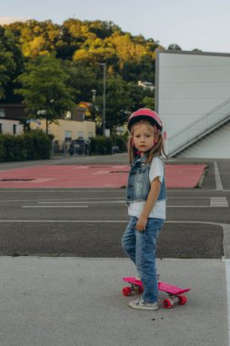 Küçük şirin kız kaykayıyla ayakta duruyor. Yüksek kalite fotoğraf