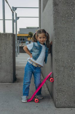 Küçük şirin kız kaykayıyla ayakta duruyor. Yüksek kalite fotoğraf