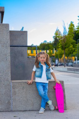 Küçük şirin kız kaykayıyla ayakta duruyor. Yüksek kalite fotoğraf