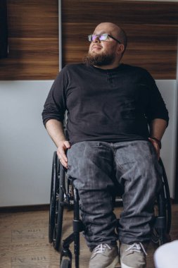 Tekerlekli sandalyede otururken pencereden bakan engelli bir genç. Yüksek kalite fotoğraf