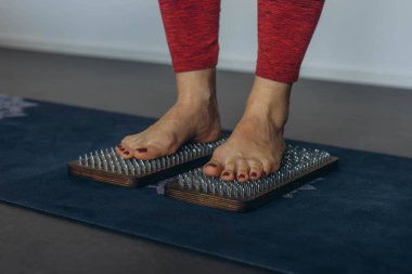 Çıplak ayaklı kadın ayağı, konsantrasyon çalışması için çivilerle tahta bir tahtanın üzerinde duruyor. Yüksek kalite fotoğraf