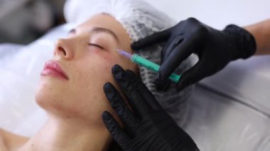 Profesyonel bir güzellik uzmanı genç bir kadının yüzüne botoks yapar. Yüksek kaliteli FullHD görüntüler