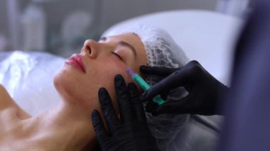 Profesyonel bir güzellik uzmanı genç bir kadının yüzüne botoks yapar. Yüksek kaliteli FullHD görüntüler
