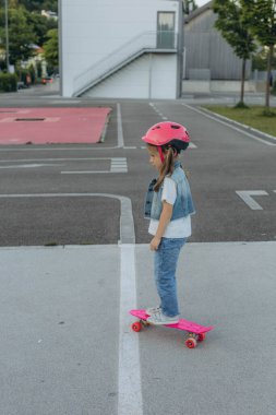 Pembe kasklı tatlı kız kaykaya biniyor. Yüksek kalite fotoğraf