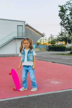 Pembe kasklı tatlı kız kaykaya biniyor. Yüksek kalite fotoğraf