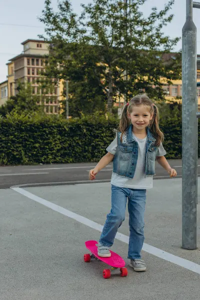 Pembe kasklı tatlı kız kaykaya biniyor. Yüksek kalite fotoğraf