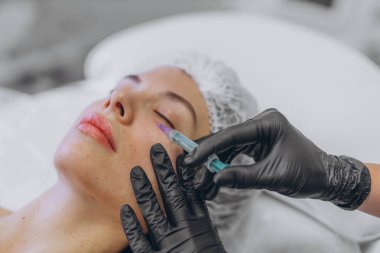 Profesyonel bir güzellik uzmanı genç bir kadının yüzüne enjekte eder. Yüksek kalite fotoğraf