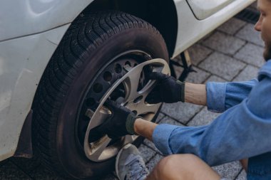 Lastik değiştirme işleminde vida sökücü fındıklı genç adam yolda lastiği değiştirirken ingiliz anahtarı kullanıyor. Yüksek kalite fotoğraf