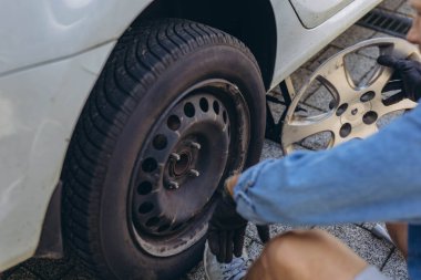 Lastik değiştirme işleminde vida sökücü fındıklı genç adam yolda lastiği değiştirirken ingiliz anahtarı kullanıyor. Yüksek kalite fotoğraf