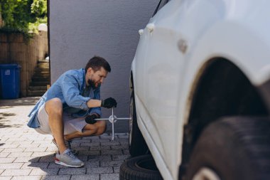 Erkek oto tamircisi, yeni lastik değiştirme işleminde tekerlek lastiğinin vidalarını sökerken, yolda lastik değiştirirken ingiliz anahtarı kullanıyor. Yüksek kalite fotoğraf