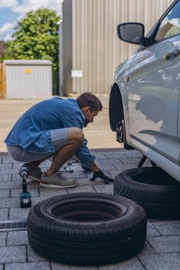 Lastik değiştirme işleminde vida sökücü fındıklı genç adam yolda lastiği değiştirirken ingiliz anahtarı kullanıyor. Yüksek kalite fotoğraf