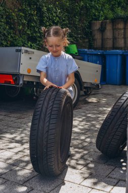 Sevimli küçük kız sıcak bir günde babasının aile arabasının tekerleğini değiştirmesine yardım ediyor. Yüksek kalite fotoğraf