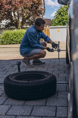 Lastik değiştirme işleminde vida sökücü fındıklı genç adam yolda lastiği değiştirirken ingiliz anahtarı kullanıyor. Yüksek kalite fotoğraf