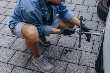 Lastik değiştirme işleminde vida sökücü fındıklı genç adam yolda lastiği değiştirirken ingiliz anahtarı kullanıyor. Yüksek kalite fotoğraf