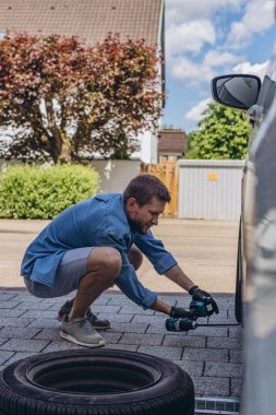 Lastik değiştirme işleminde vida sökücü fındıklı genç adam yolda lastiği değiştirirken ingiliz anahtarı kullanıyor. Yüksek kalite fotoğraf