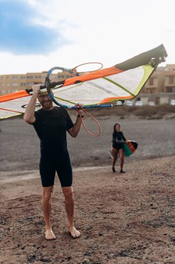 Kanarya Adası, Tenerife-14 Aralık 2023 Erkekler ve kız profesyonel sörfçü uçurtma ve tahtasıyla kumsalda duruyorlar. Rüzgâr sörfü, Ekstrem Spor. Yüksek kalite fotoğraf