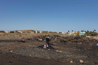 Kanarya Adası, Tenerife-14 Aralık 2023 Erkekler ve kız profesyonel sörfçü uçurtma ve tahtasıyla kumsalda duruyorlar. Rüzgâr sörfü, Ekstrem Spor. Yüksek kalite fotoğraf