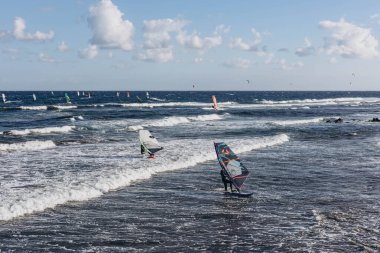 Kanarya Adası, Tenerife-14 Aralık 2023 Erkekler ve kız profesyonel sörfçü uçurtma ve tahtasıyla kumsalda duruyorlar. Rüzgâr sörfü, Ekstrem Spor. Yüksek kalite fotoğraf