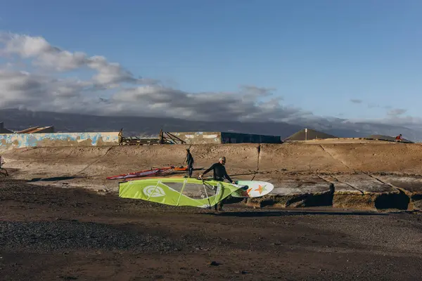 Stock image Canary Island, Tenerife-December14,2023.Men and girl professional surfer standing on the sandy beach with his kite and board. Windsurfing, Extreme Sport. High quality photo