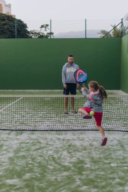 Babası kızına raket tenisi öğretiyor. Yüksek kalite fotoğraf