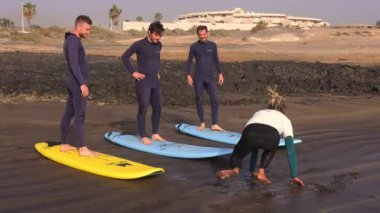 Canary Adası, Tenerife-14 Aralık 2023 sörfçüleri okyanusta sörf yapmaya gidiyorlar. Koç gruba nasıl sörf yapılacağını gösteriyor. Yüksek kaliteli FullHD görüntüler